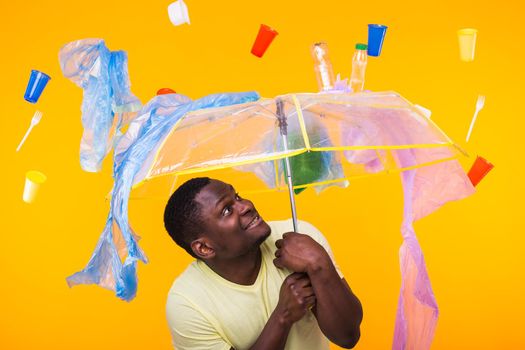 World Environment Day, plastic recycling problem and environmental disaster concept - Terrified man on yellow background with trash.