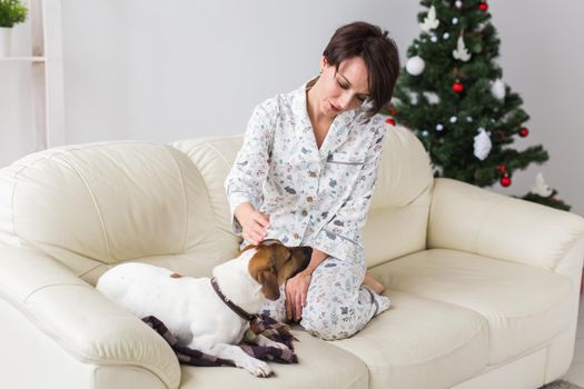 Happy young woman with lovely dog in living room with christmas tree. Holidays.