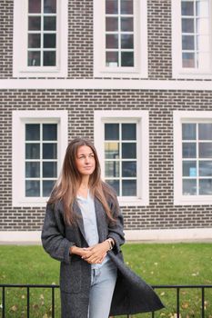 Romantic and cheerful young woman. Portrait of a Beautiful girl in jeans, a blue shirt, and a light coat. Walks the streets of the city