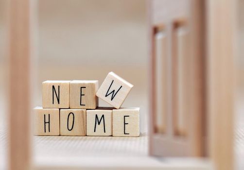 New Home text written with wooden cubes background with symbol of cozy little house with blurred background design, purchase real estate,mortgage loan, property owner concept background close up
