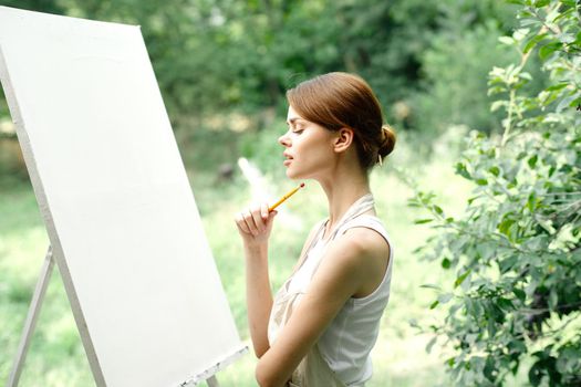 Cheerful woman artist nature easel creative art. High quality photo