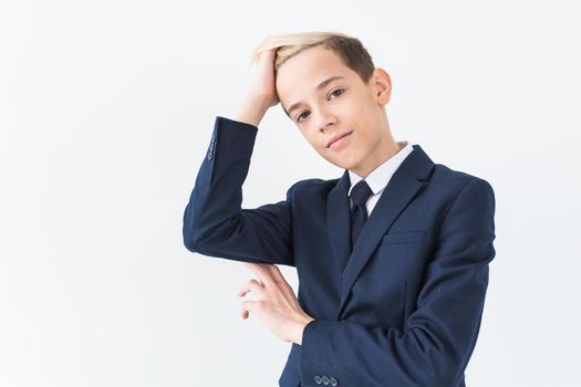 Portrait of stylish school boy teenager in white shirt and jacket against white background with copy space