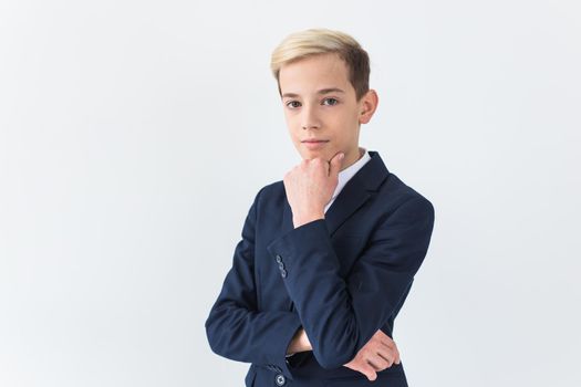 Portrait of stylish school boy teenager in white shirt and jacket against white background with copy space