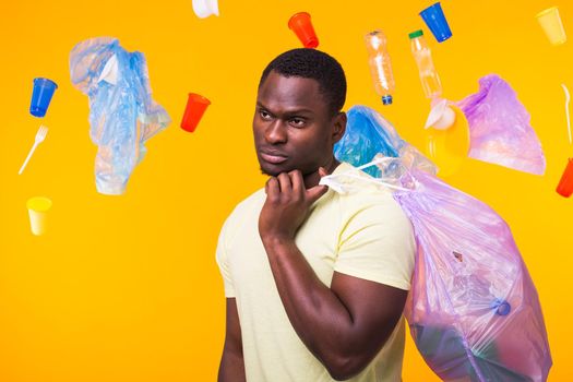 Problem of trash, plastic recycling, pollution and environmental concept - man carrying garbage bag on yellow background.