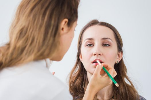 Beauty and cosmetics concept - Makeup artist doing professional make up of young woman.