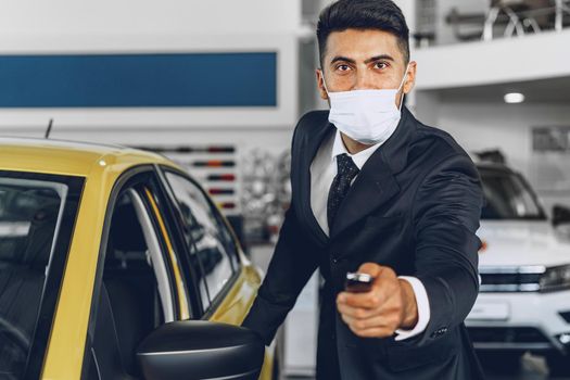 Man car dealer wearing protective medical mask on his working place, coronavirus prevention concept