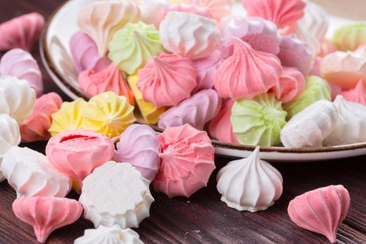 Colorful sweet meringue cookies assortment on wooden table close up