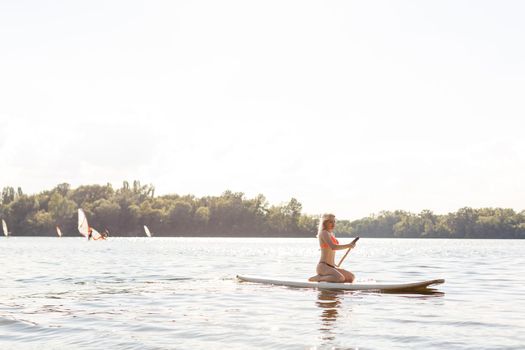 woman with a paddle on the blackboard. legs of a slender girl on stand up paddle board.