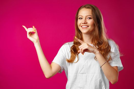 Portrait charming pretty cheerful girl showing copy space with her finger