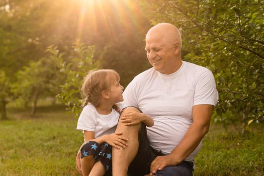 Little girl spending time with grandfather in the park.