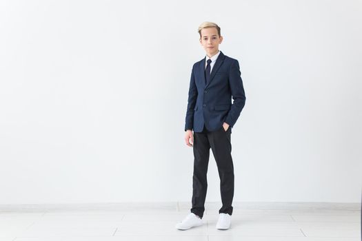 Portrait of stylish school boy teenager in white shirt and jacket against white background with copy space