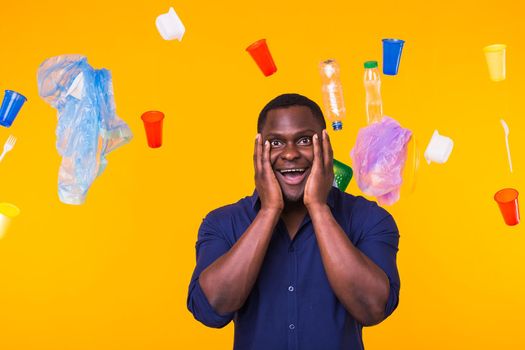 World Environment Day, plastic recycling problem and environmental disaster concept - Terrified man on yellow background with trash.