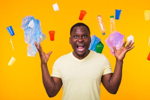 World Environment Day, plastic recycling problem and environmental disaster concept - Terrified man on yellow background with trash.