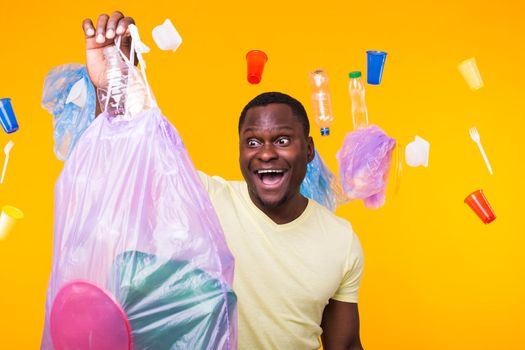 Problem of trash, plastic recycling, pollution and environmental concept - confused man carrying garbage bag on yellow background.