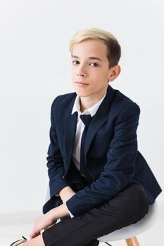 Portrait of stylish school boy teenager in white shirt and jacket against white background with copy space