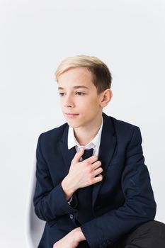 Portrait of stylish school boy teenager in white shirt and jacket against white background with copy space