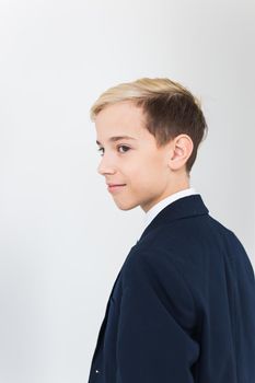 Portrait of stylish school boy teenager in white shirt and jacket against white background with copy space