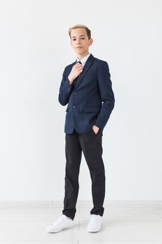 Portrait of stylish school boy teenager in white shirt and jacket against white background with copy space