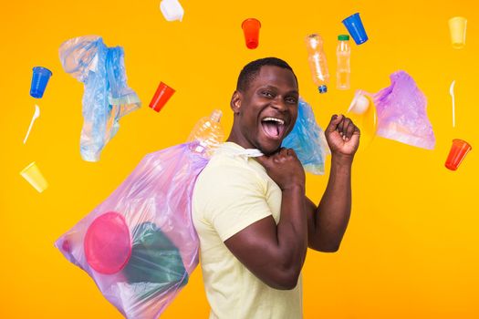 Problem of trash, plastic recycling, pollution and environmental concept - confused man carrying garbage bag on yellow background.