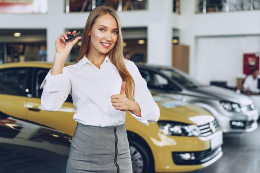 Young happy woman buyer/seller near the car with keys in hand close up