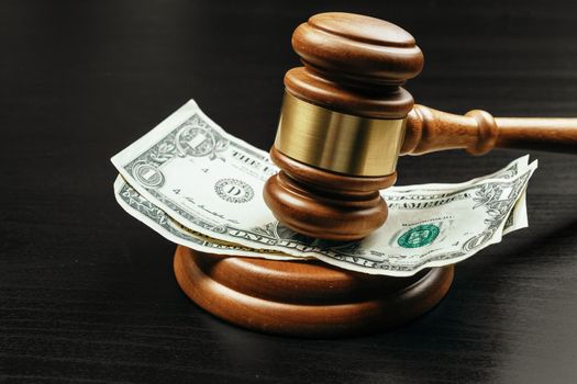 Business finance, corruption concept. Wooden gavel with american dollars. Close up.