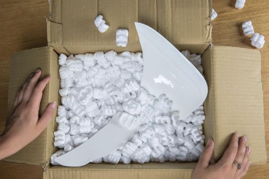 Broken plate in damaged cardboard box top view, damaged home delivery unpacking box close up