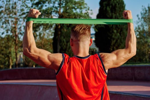 athletic man on the sports ground rubber band exercise. High quality photo