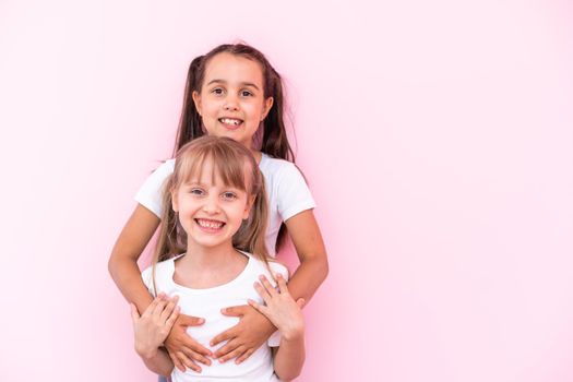 Two little girls - best friends, isolated over on a pink background