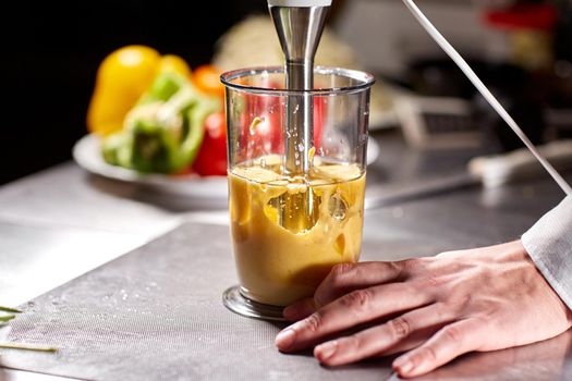 Beating of homemade mayonnaise with olive oil. Mix ingredients for sauce. The chef uses a blender. Step by step sauce preparation.