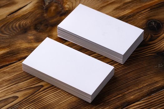 Stack of white business cards on brown wooden background, close up