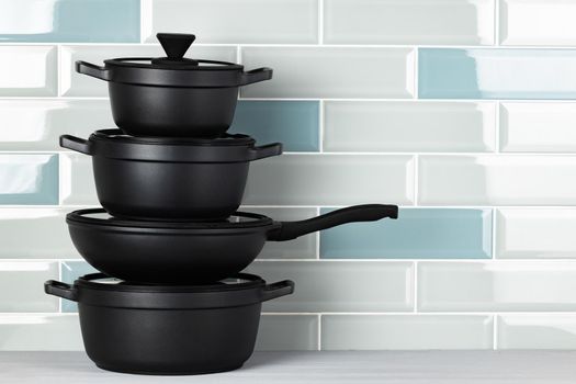 New black cookware against blue tile wall close up