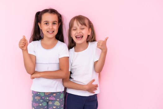 Two little girls - best friends, isolated over on a pink background