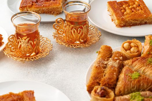 Various Turkish sweets and cup of tea on white textured background, close up