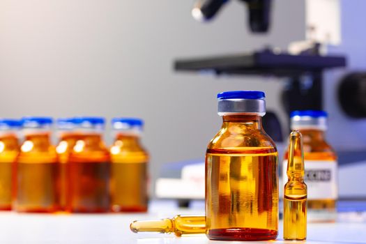 Medical vial with medication near microscope close up photo