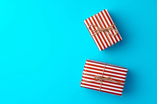 Red and white striped gift box on blue background top view