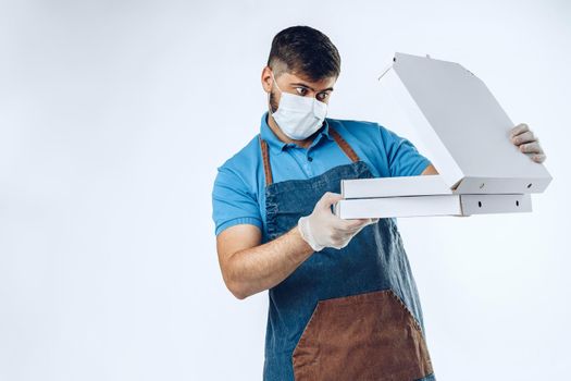 Pizza delivery man in medical gloves and mask against grey background. Safe service while coronavirus covid-19 outbreak