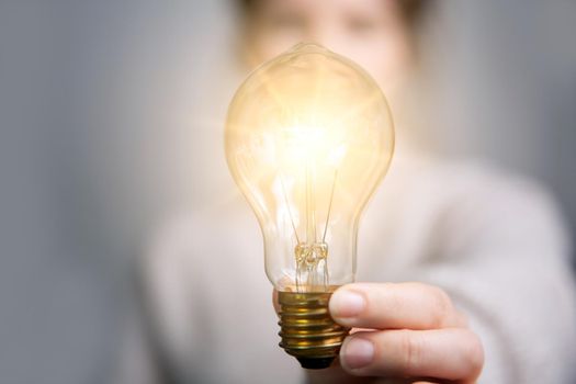 Female hand holding a shining light bulb, Great idea, innovation and inspiration, business concept background modern retro design