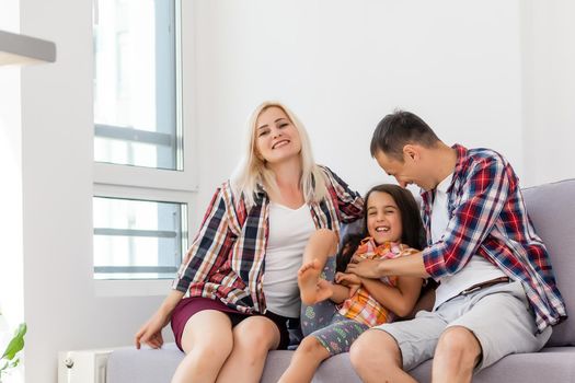 Smiling young parents and their child are very happy, they are at home