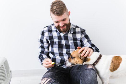 Dog carrying bags and pets owner concept - Attractive cheerful male in plaid shirt holds favourite pet. Happy bearded man with his jack russell terrier.