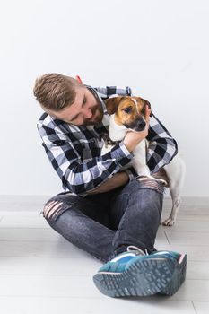 Dog carrying bags and pets owner concept - Attractive cheerful male in plaid shirt holds favourite pet. Happy bearded man with his jack russell terrier.