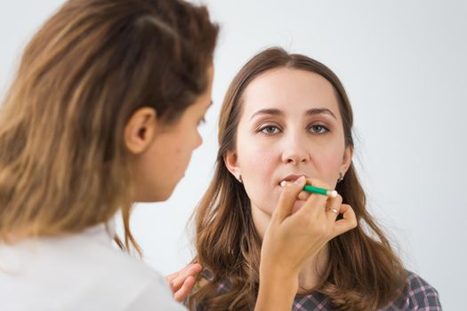 Beauty and cosmetics concept - Makeup artist doing professional make up of young woman.