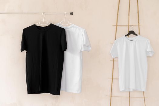 White and black T-shirts on hangers for design presentation, copy space