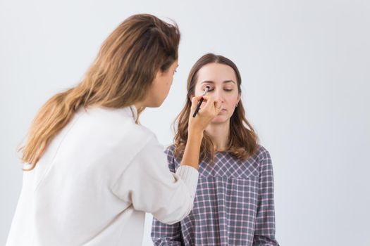 Beauty and cosmetics concept - Makeup artist doing professional make up of young woman.