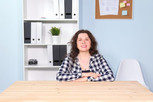 Portrait of business girl sitting on table in office