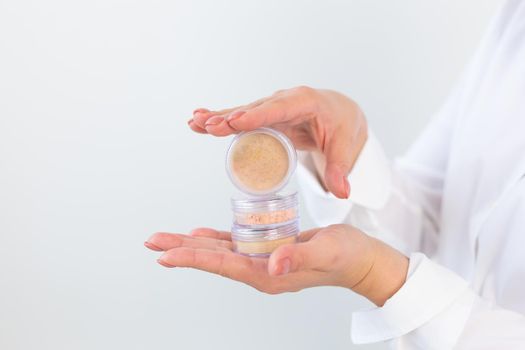 Woman hand holding loose beige powder on a white background. Isolated background. Space for text