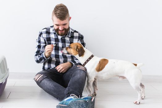 Dog carrying bags and pets owner concept - Attractive cheerful male in plaid shirt holds favourite pet. Happy bearded man with his jack russell terrier.