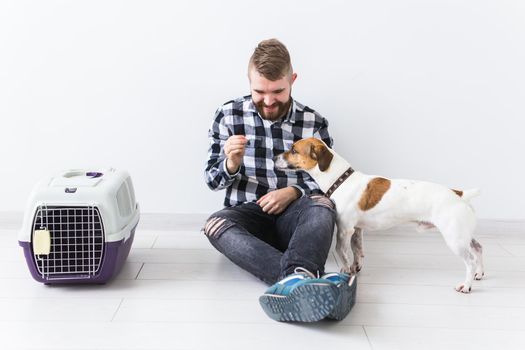 Dog carrying bags and pets owner concept - Attractive cheerful male in plaid shirt holds favourite pet. Happy bearded man with his jack russell terrier.