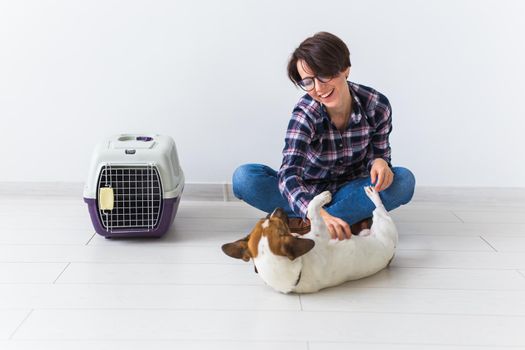 Dog carrying bags and pets owner concept - Attractive cheerful female in plaid shirt holds favourite pet. Happy woman with her jack russell terrier.