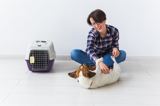 Dog carrying bags and pets owner concept - Attractive cheerful female in plaid shirt holds favourite pet. Happy woman with her jack russell terrier.