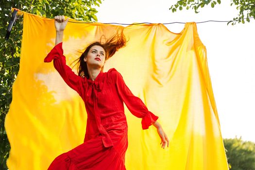 beautiful woman posing in red dress outdoors yellow cloth. High quality photo